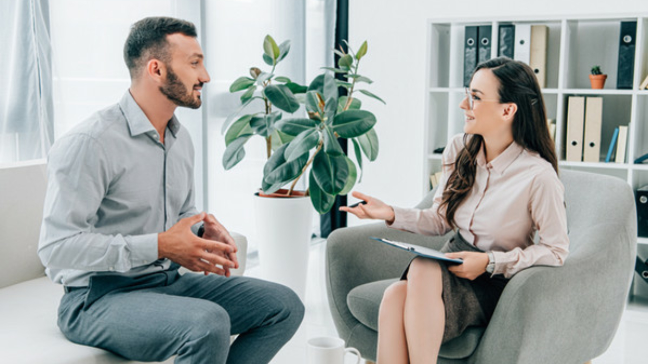 smiling psychiatrist with clipboard talking with happy patient in office